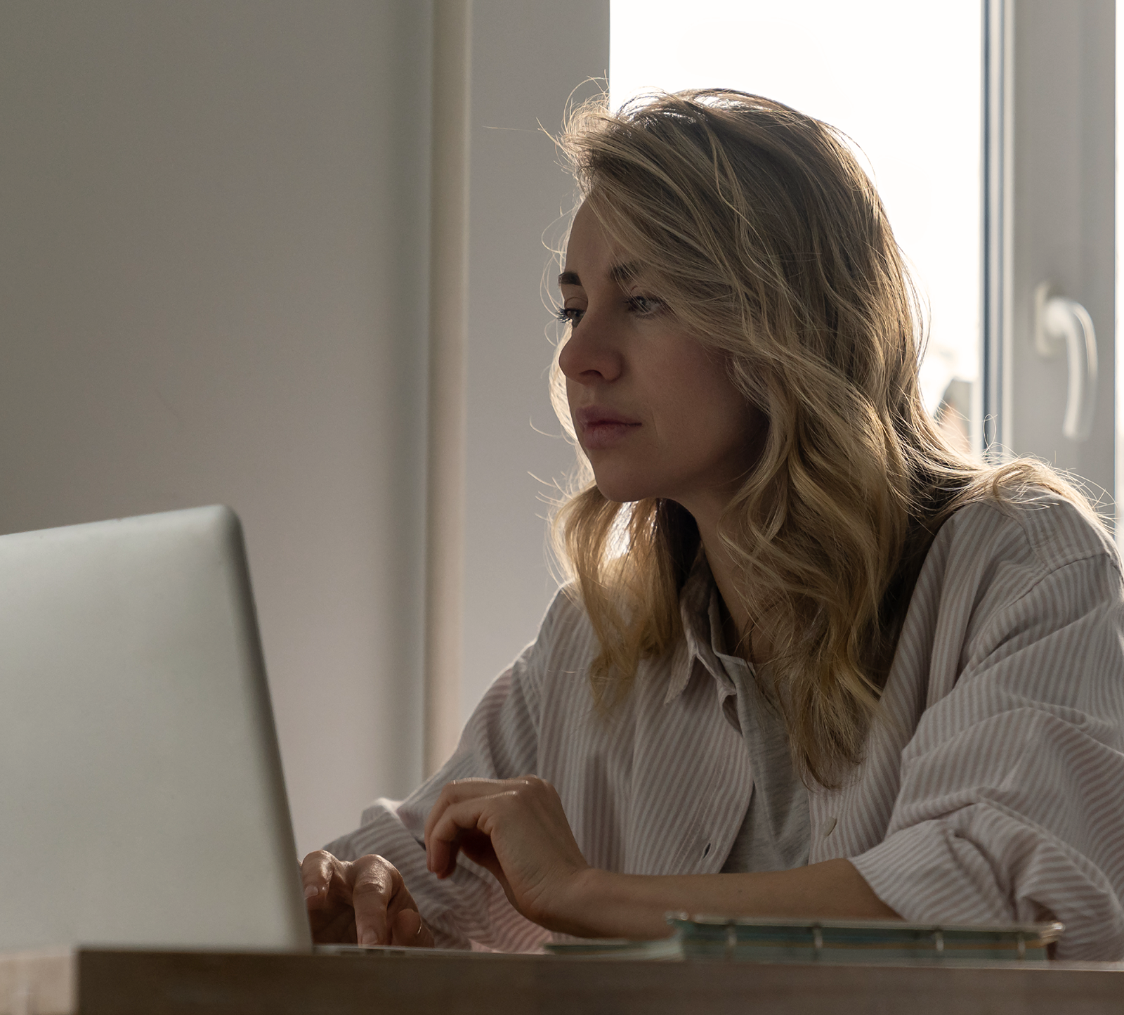 Professional working at a laptop by a window